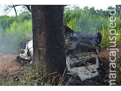 Carro tomba após bater em árvore, pega fogo, mas ocupantes se salvam