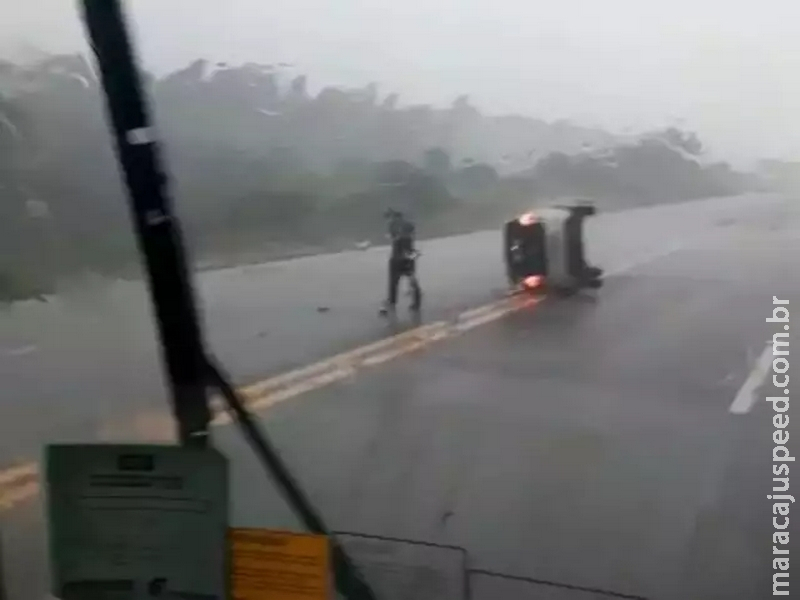 Condutor perde controle em rodovia molhada, carro capota e para no meio da pista